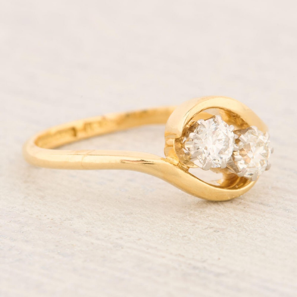 An 18ct yellow gold crossover bypass ring featuring two claw-set round brilliant diamonds. View III