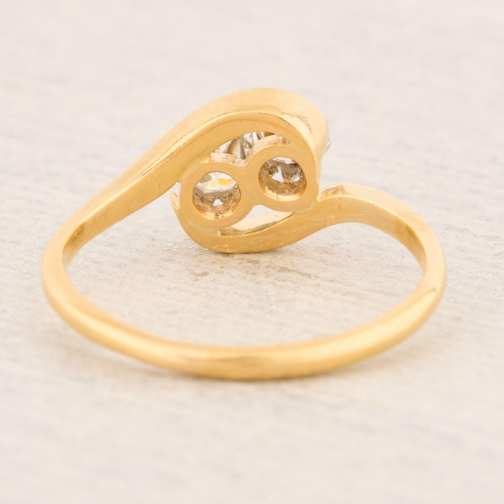 An 18ct yellow gold crossover bypass ring featuring two claw-set round brilliant diamonds. View V