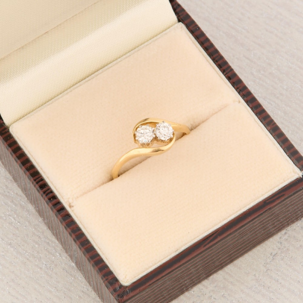 An 18ct yellow gold crossover bypass ring featuring two claw-set round brilliant diamonds. View VIII
