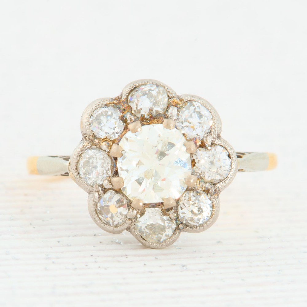 An 18ct gold ring featuring a floral-shaped cluster of round diamonds set in a platinum head.