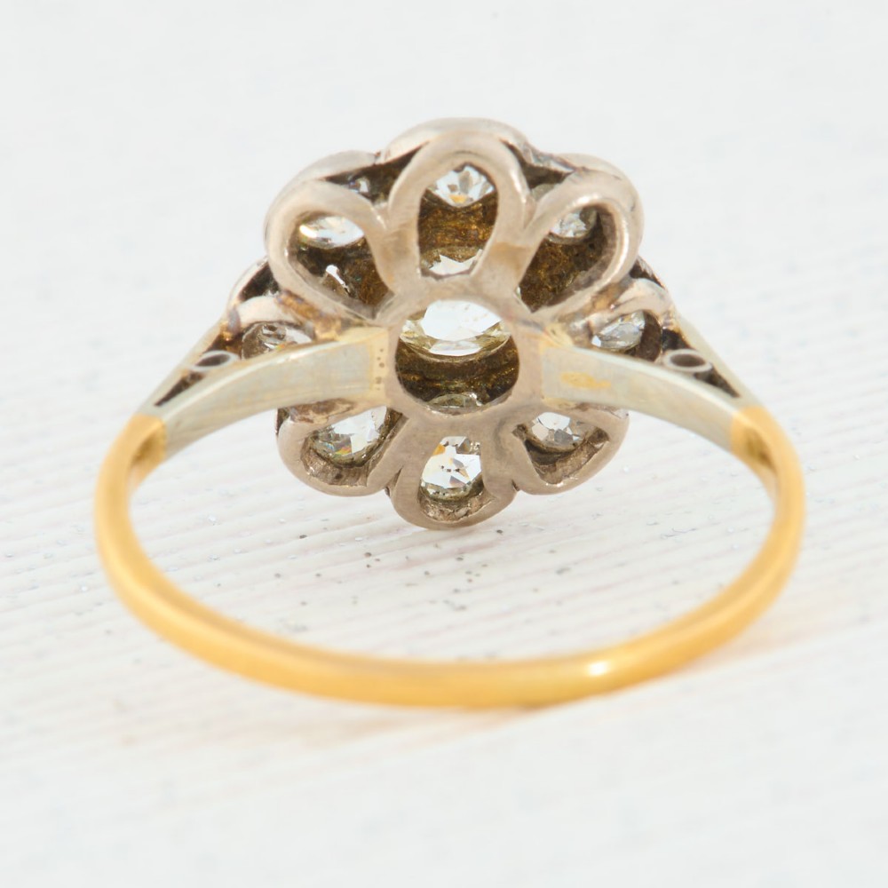 An 18ct gold ring featuring a floral-shaped cluster of round diamonds set in a platinum head. View V