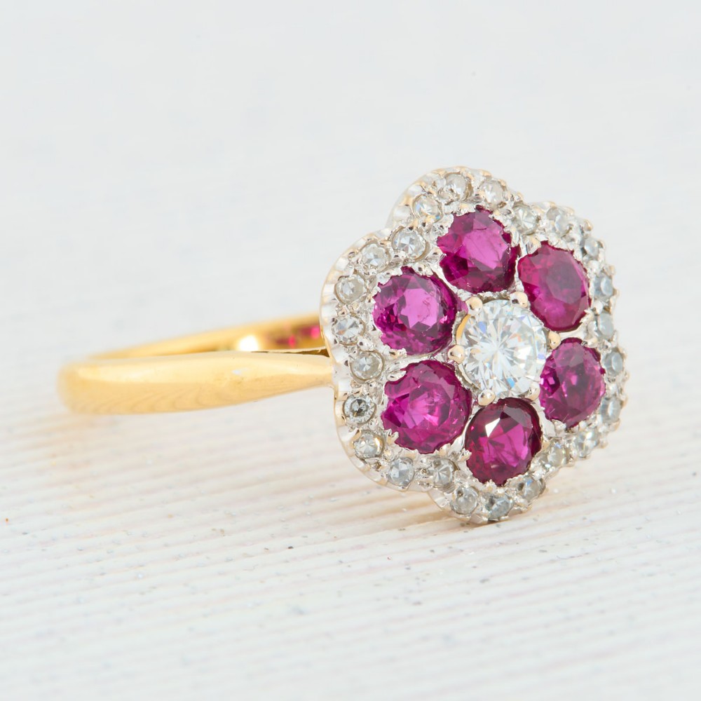 An 18ct yellow gold cluster ring with a brilliant central diamond surrounded by six round rubies and an outer diamond halo. View III
