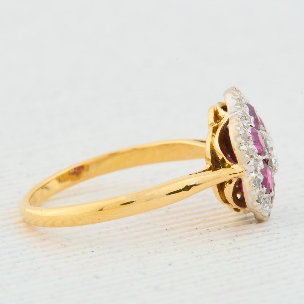 An 18ct yellow gold cluster ring with a brilliant central diamond surrounded by six round rubies and an outer diamond halo. View IV