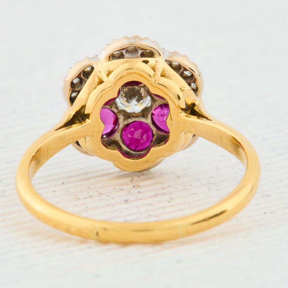 An 18ct yellow gold cluster ring with a brilliant central diamond surrounded by six round rubies and an outer diamond halo. View V