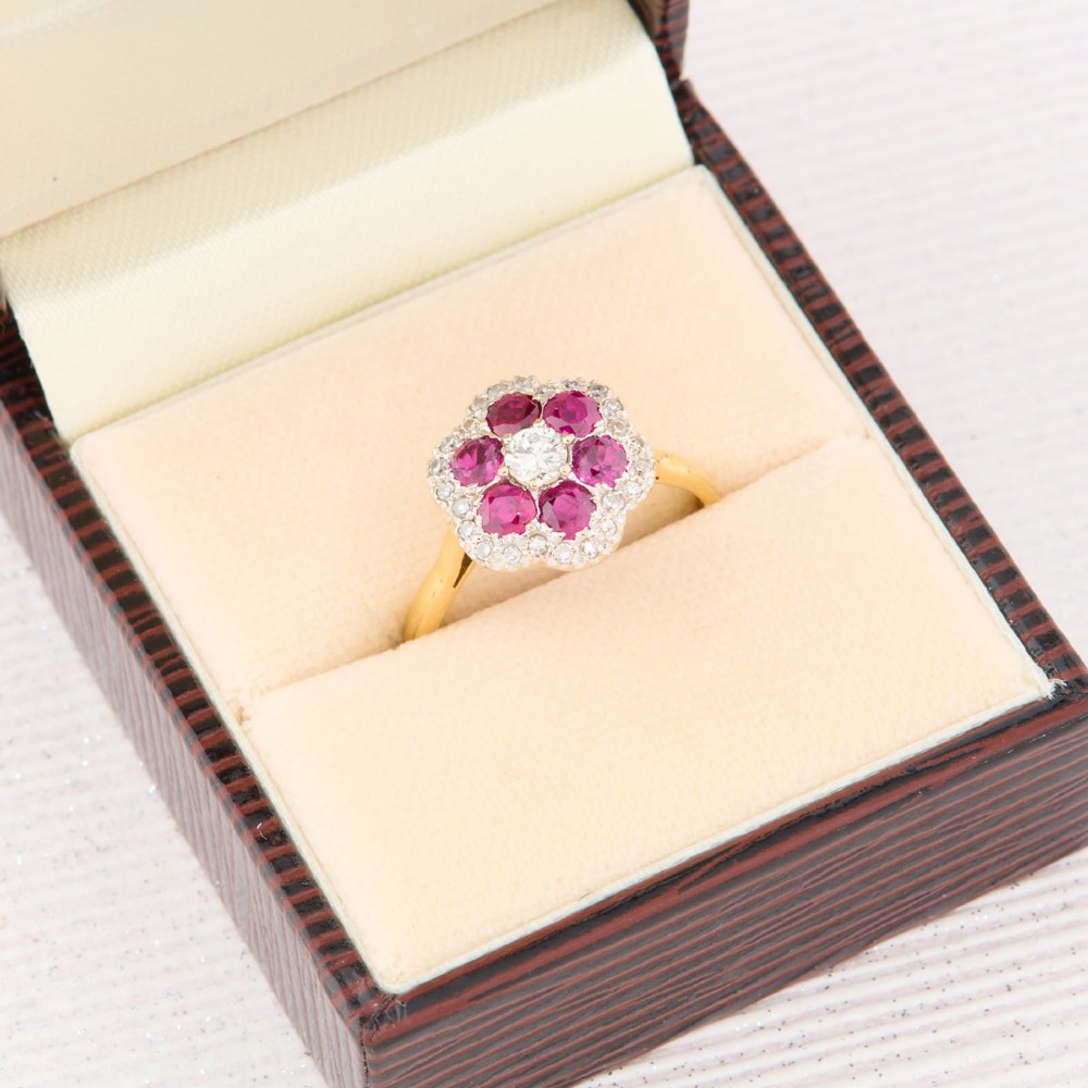 An 18ct yellow gold cluster ring with a brilliant central diamond surrounded by six round rubies and an outer diamond halo. View VIII