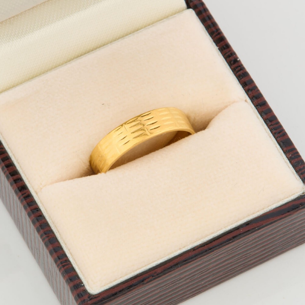 A wide 22ct yellow gold wedding ring featuring an engraved ribbed geometric pattern along the exterior surface and internal hallmarks. View VI