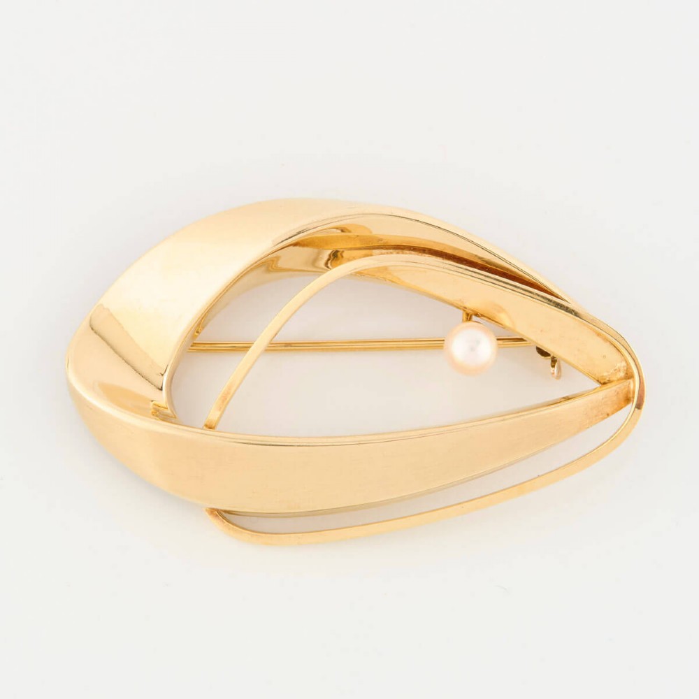 A 9ct gold brooch featuring a sweeping, abstract curved frame holding a single white pearl at its centre. View III