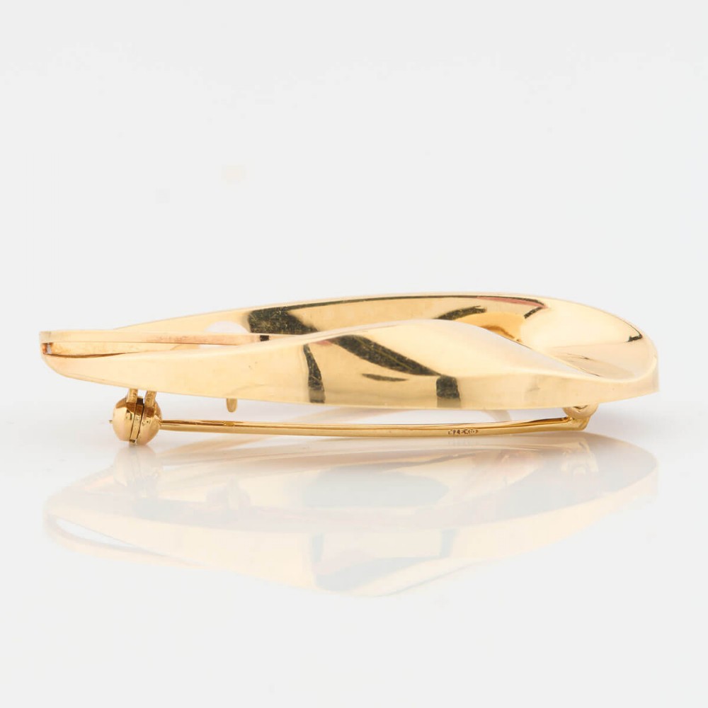A 9ct gold brooch featuring a sweeping, abstract curved frame holding a single white pearl at its centre. View V