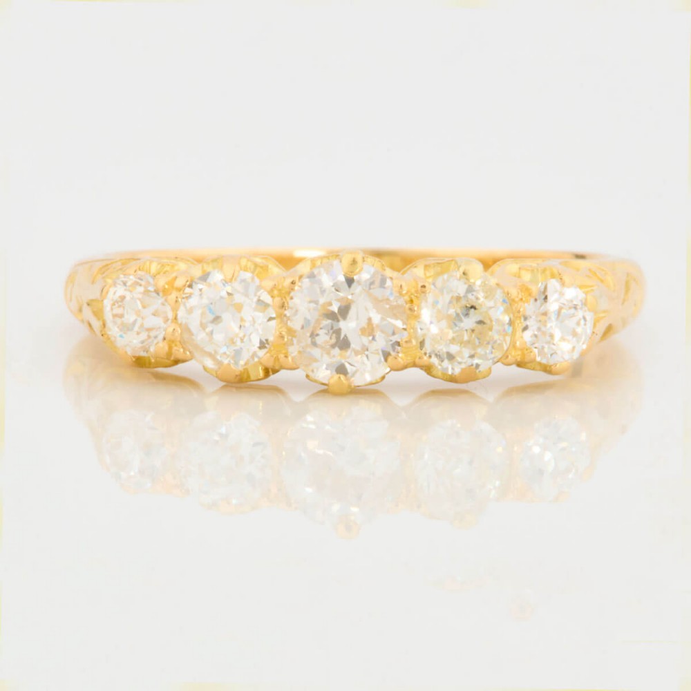 An 18ct yellow gold five-stone ring set with graduated old cut diamonds within a carved gallery.
