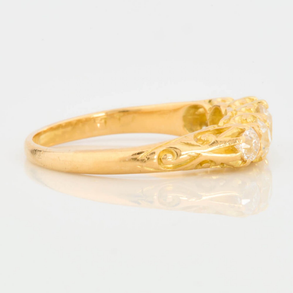 An 18ct yellow gold five-stone ring set with graduated old cut diamonds within a carved gallery. View IV