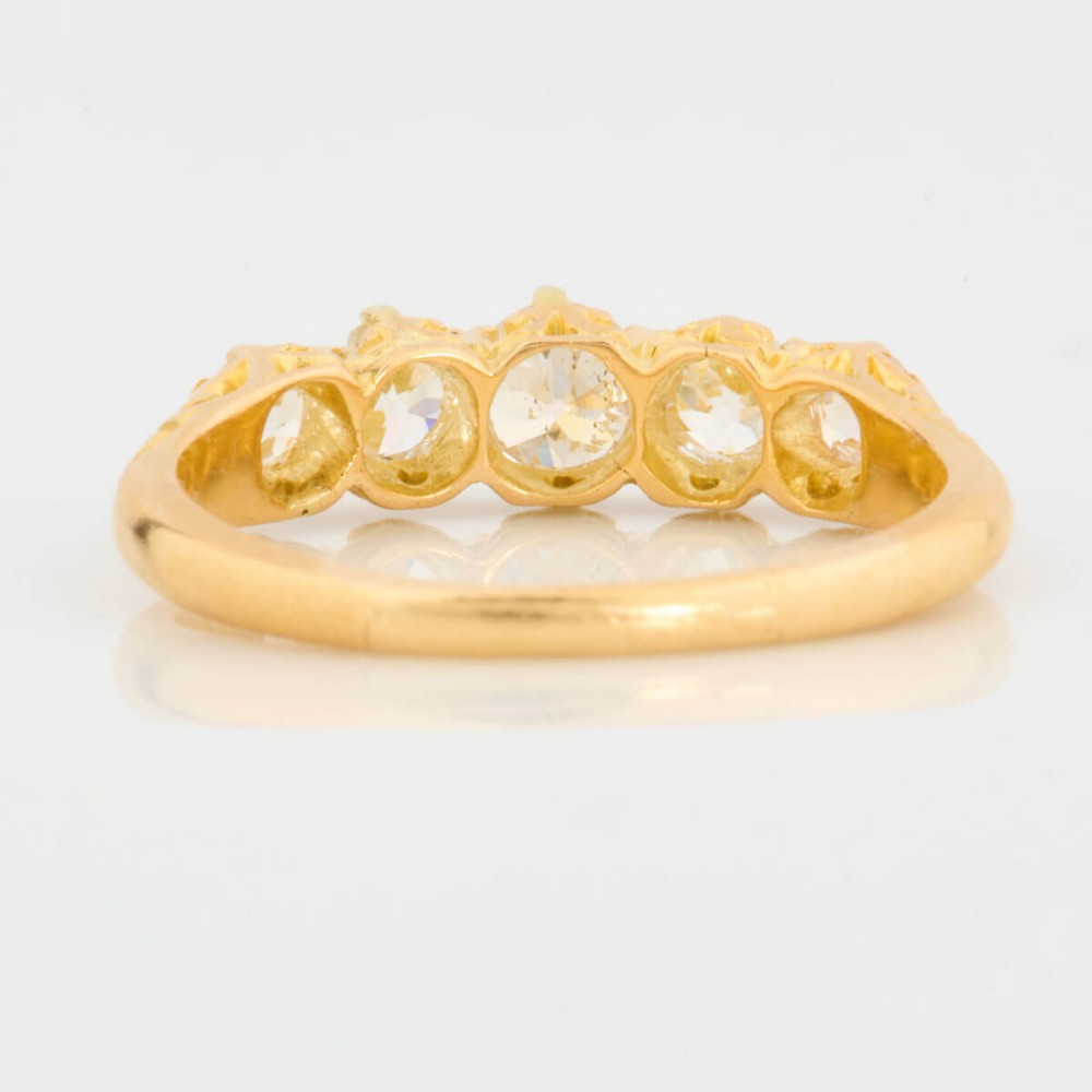An 18ct yellow gold five-stone ring set with graduated old cut diamonds within a carved gallery. View V