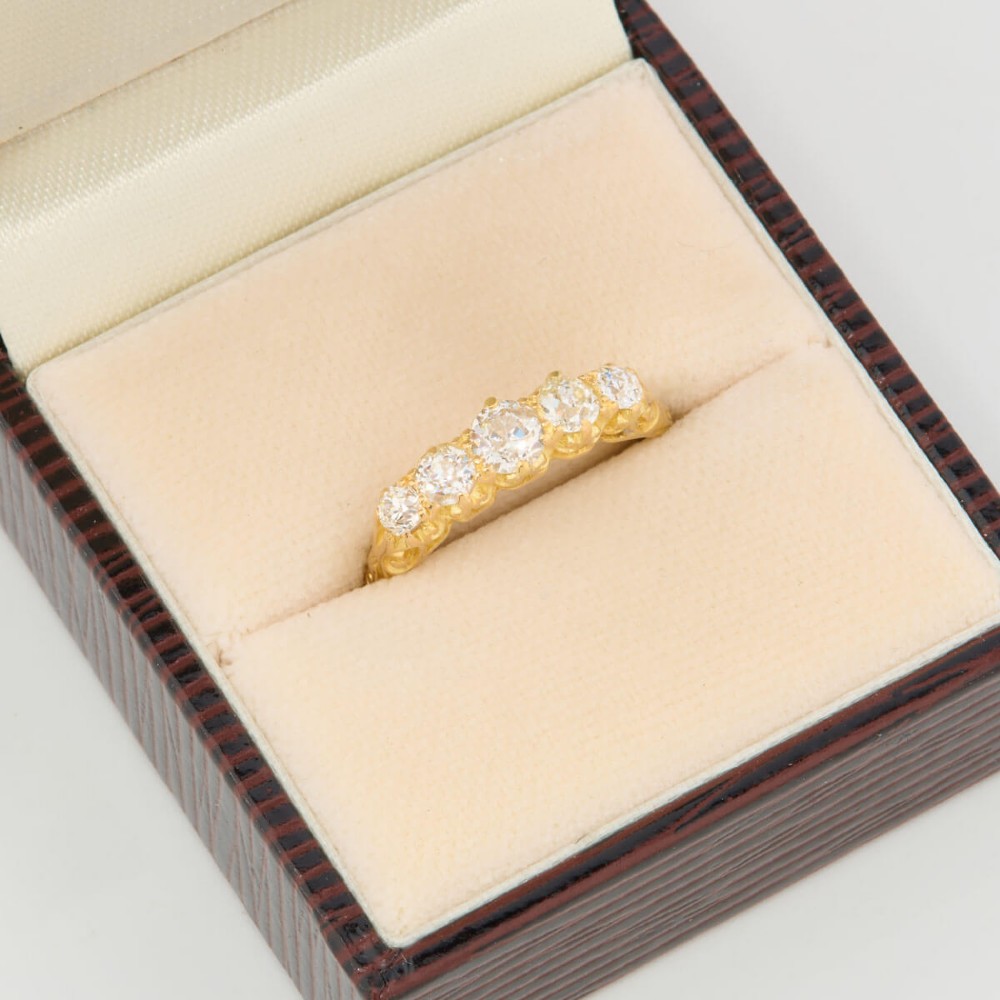 An 18ct yellow gold five-stone ring set with graduated old cut diamonds within a carved gallery. View VII