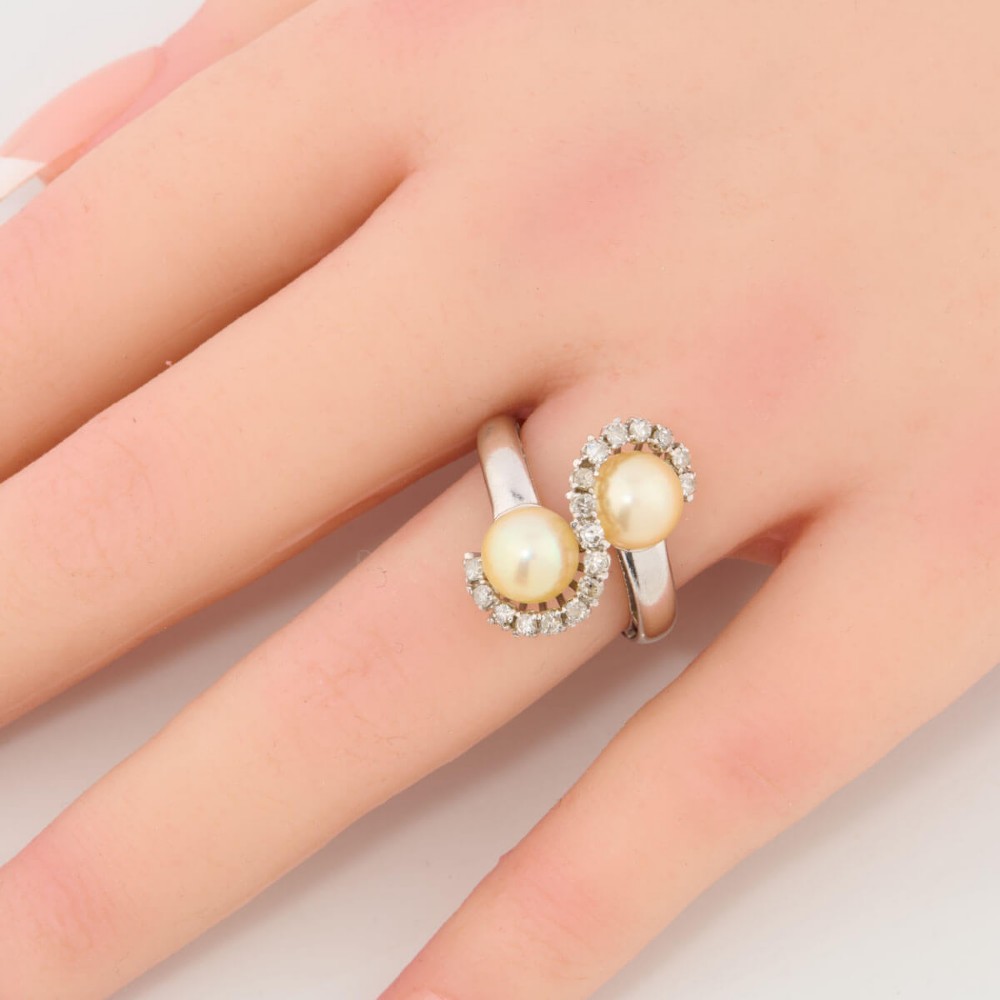 An 18ct white gold swirl cocktail ring featuring two central cream pearls wrapped in an S-shaped band set with small round diamonds. View II