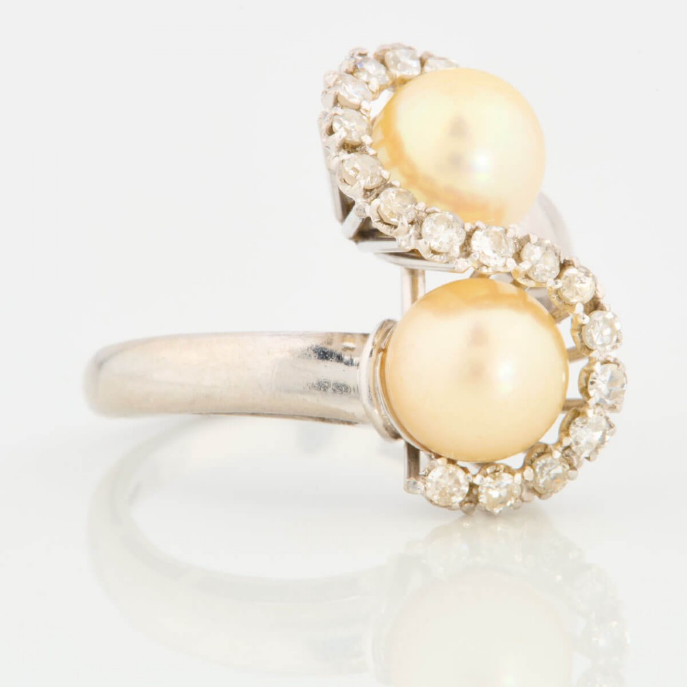 An 18ct white gold swirl cocktail ring featuring two central cream pearls wrapped in an S-shaped band set with small round diamonds. View III