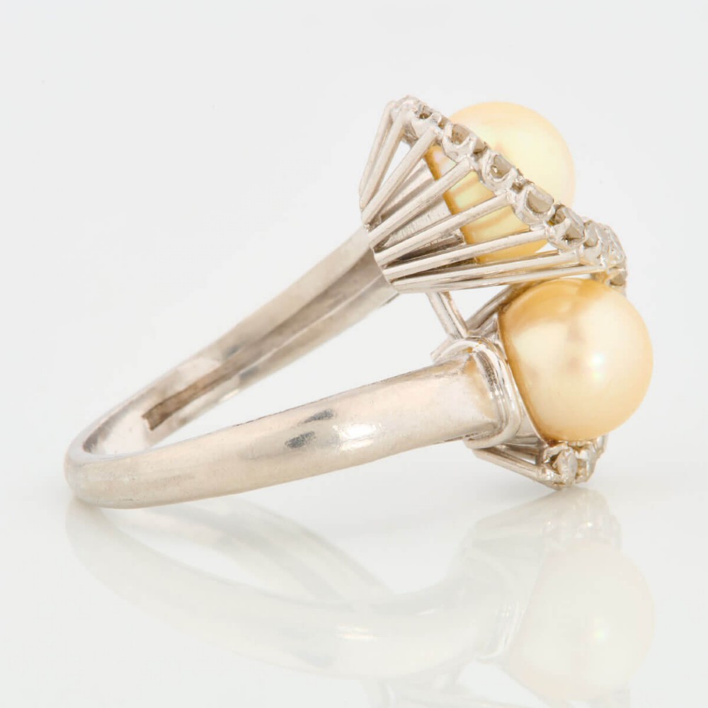 An 18ct white gold swirl cocktail ring featuring two central cream pearls wrapped in an S-shaped band set with small round diamonds. View IV