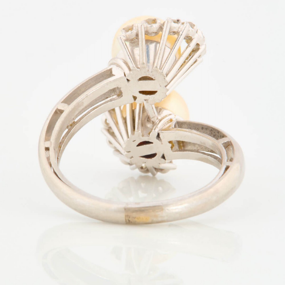 An 18ct white gold swirl cocktail ring featuring two central cream pearls wrapped in an S-shaped band set with small round diamonds. View V