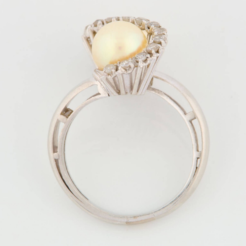 An 18ct white gold swirl cocktail ring featuring two central cream pearls wrapped in an S-shaped band set with small round diamonds. View VI