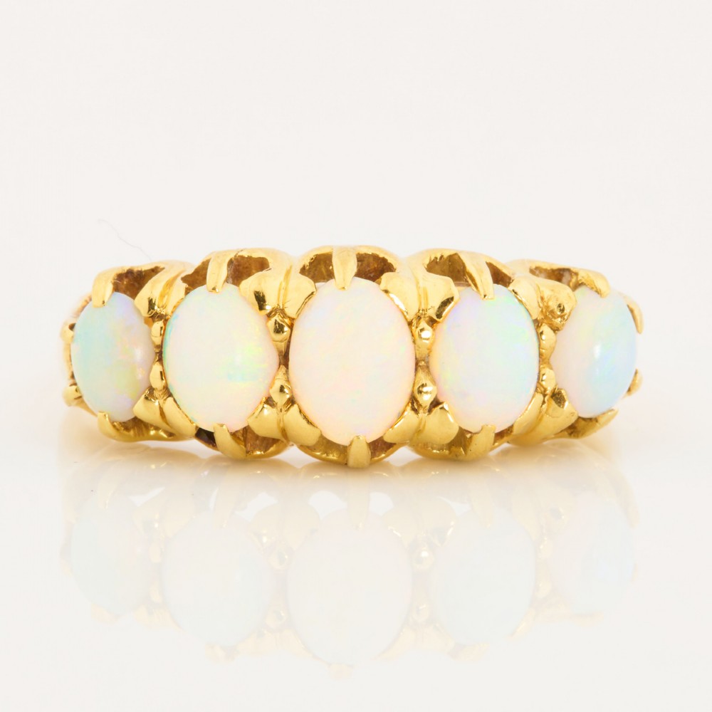 An 18ct yellow gold ring featuring five oval cabochon opals in a carved claw setting.