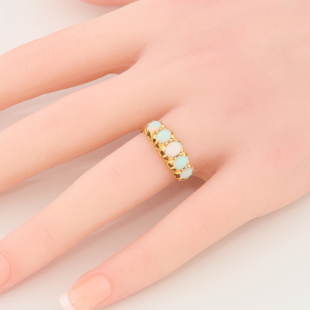An 18ct yellow gold ring featuring five oval cabochon opals in a carved claw setting. View II