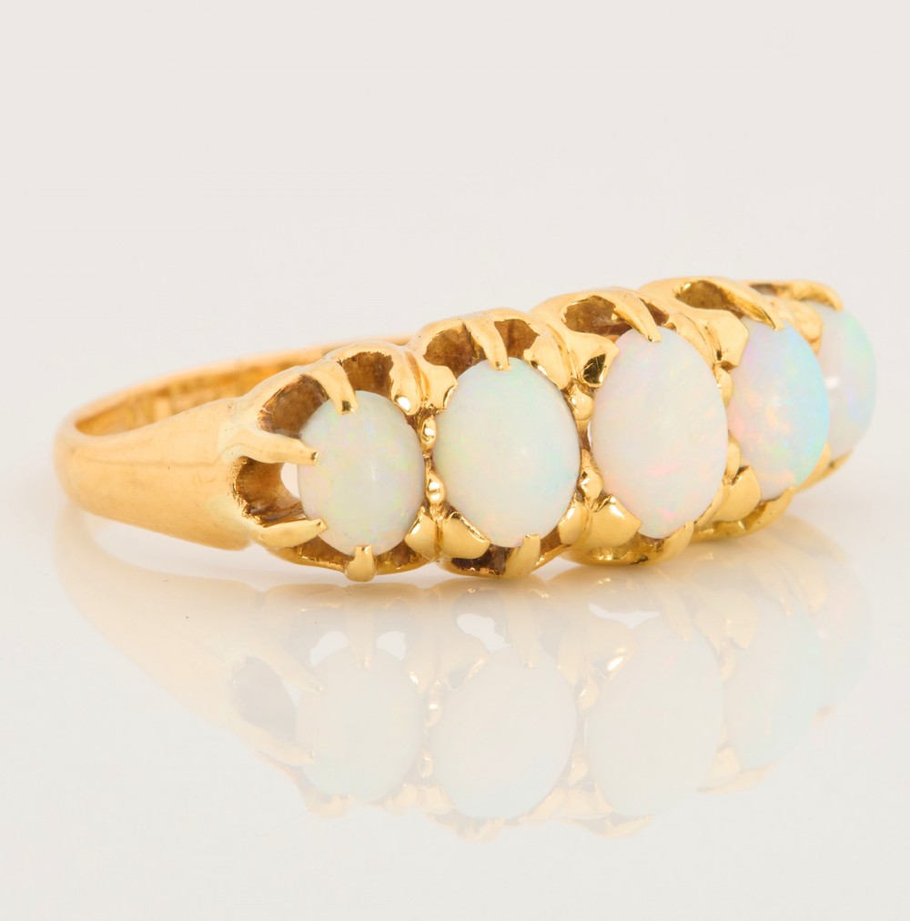 An 18ct yellow gold ring featuring five oval cabochon opals in a carved claw setting. View III