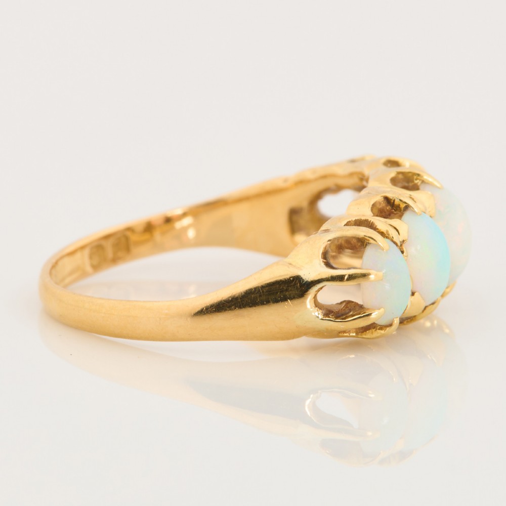 An 18ct yellow gold ring featuring five oval cabochon opals in a carved claw setting. View IV