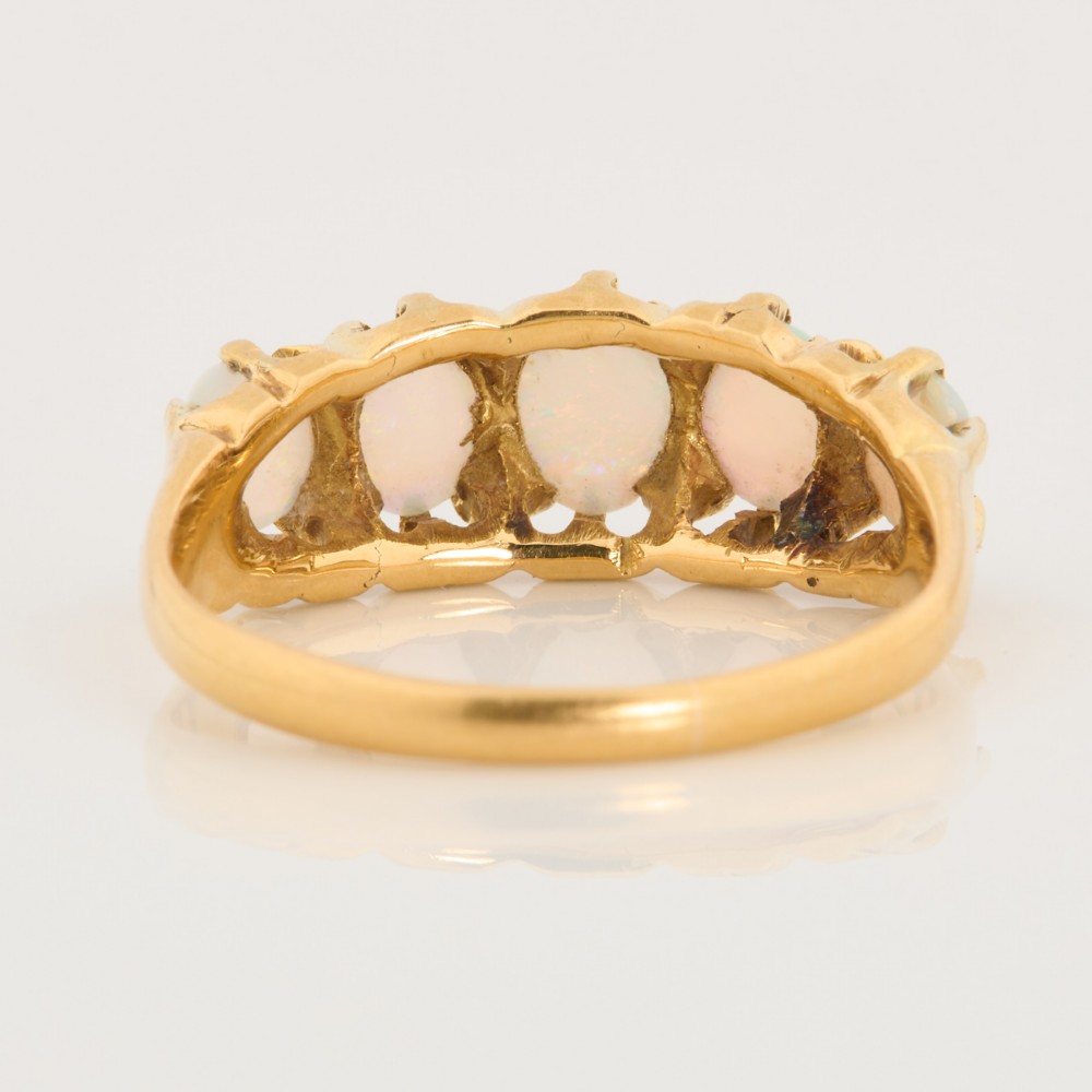 An 18ct yellow gold ring featuring five oval cabochon opals in a carved claw setting. View V