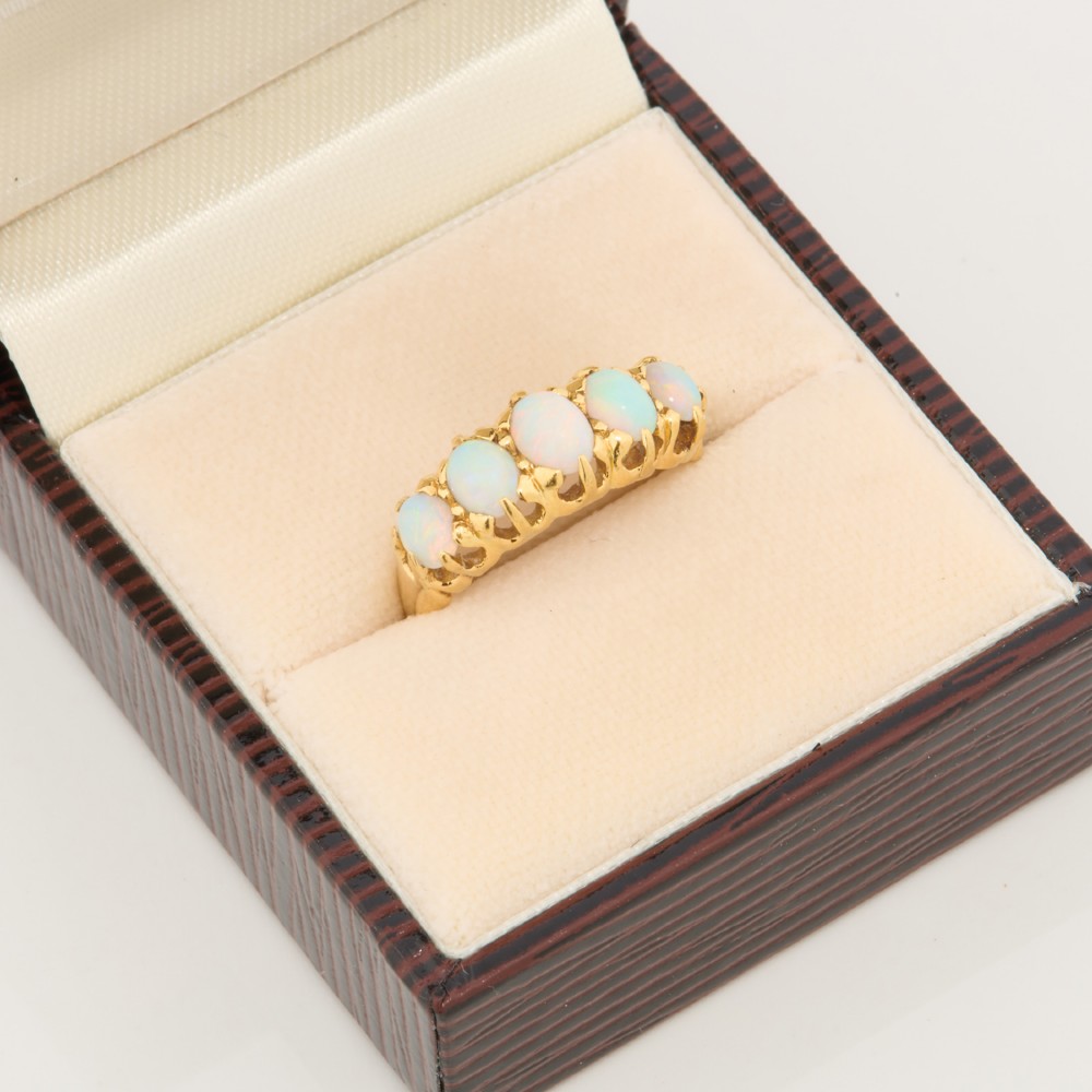 An 18ct yellow gold ring featuring five oval cabochon opals in a carved claw setting. View VIII