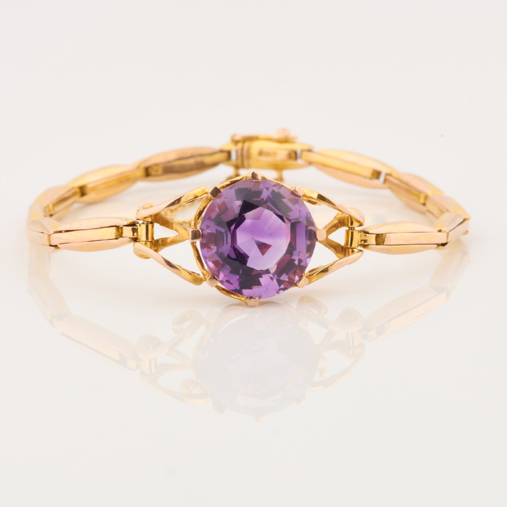 A 9ct yellow gold link bracelet featuring a central round faceted purple amethyst held in a claw setting.