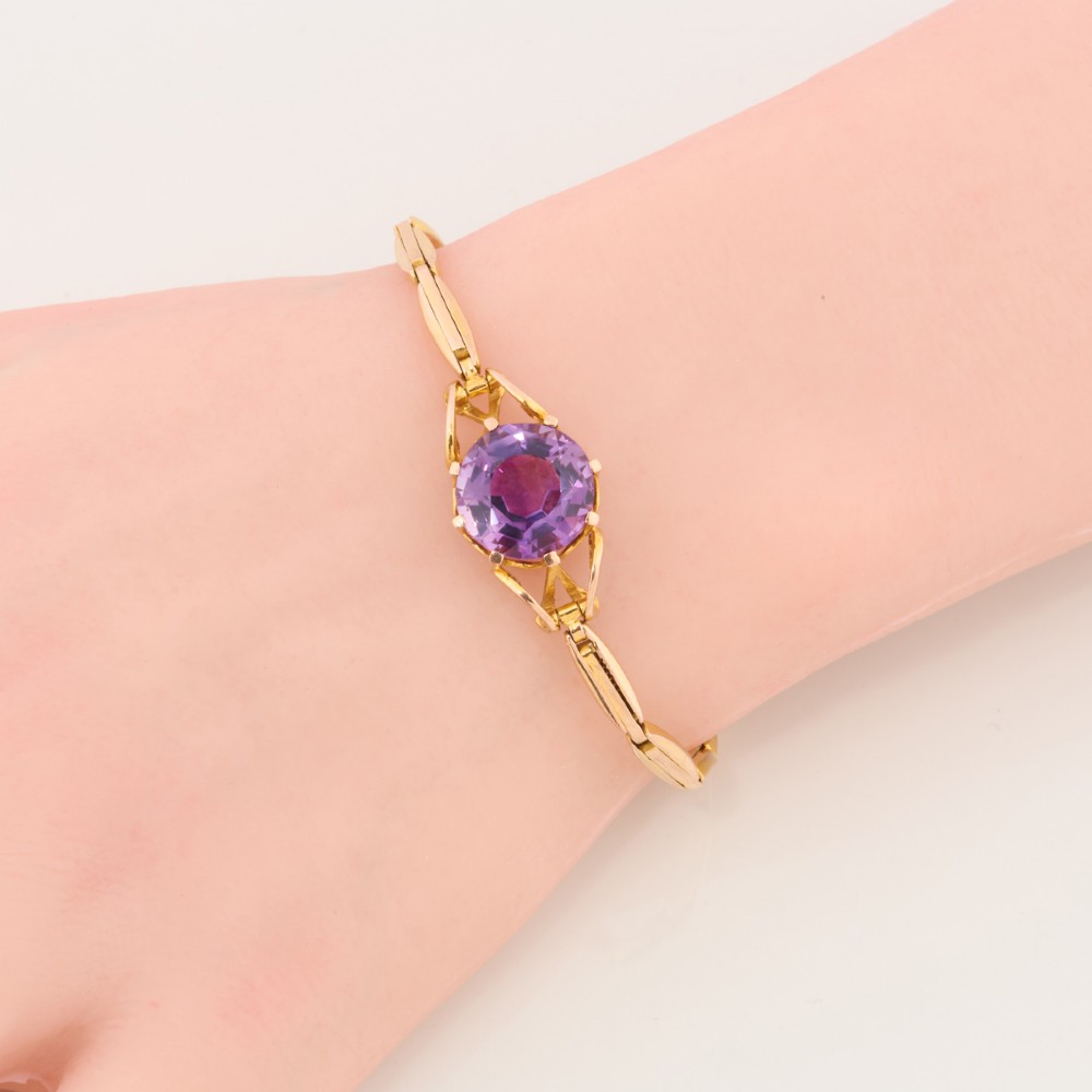 A 9ct yellow gold link bracelet featuring a central round faceted purple amethyst held in a claw setting. View II