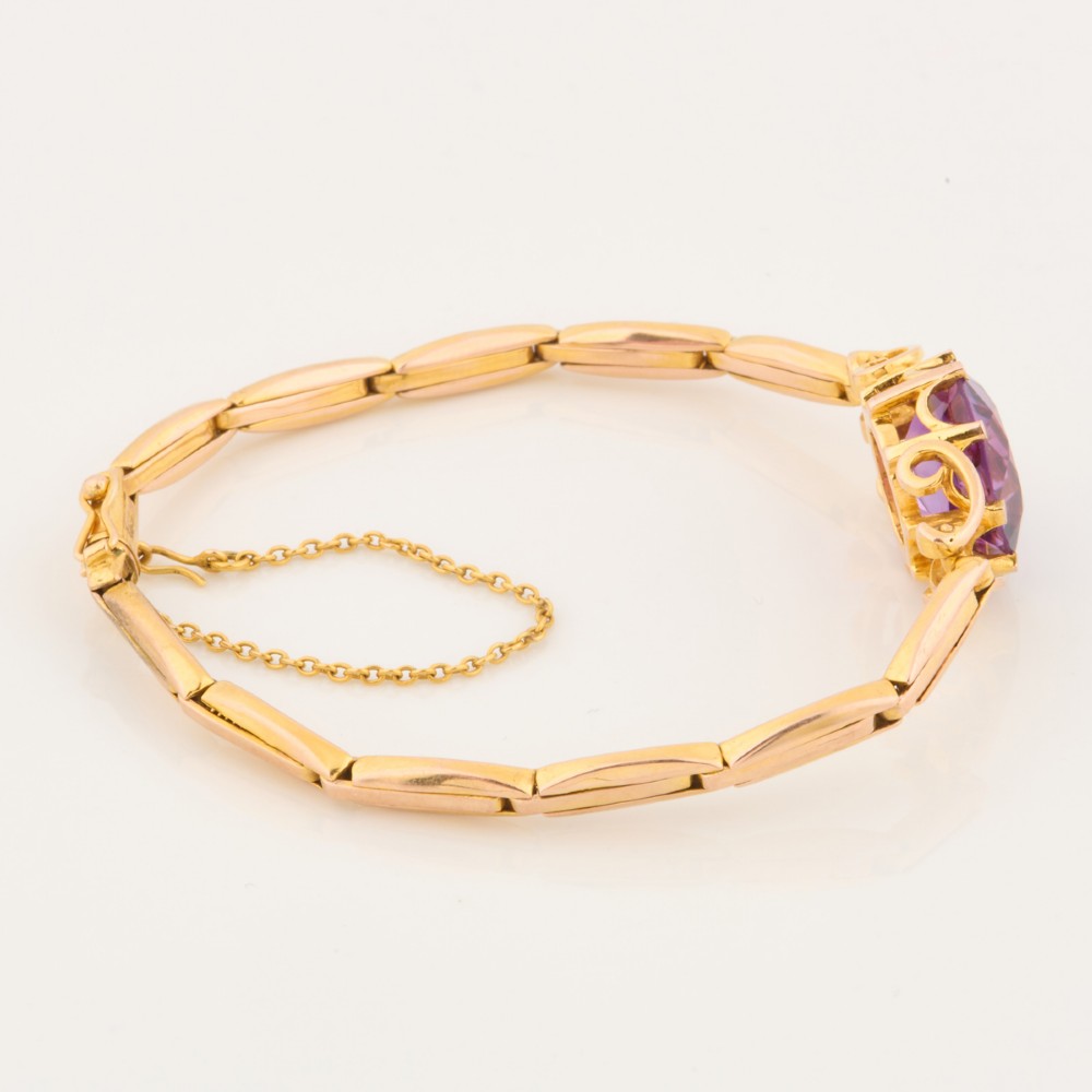 A 9ct yellow gold link bracelet featuring a central round faceted purple amethyst held in a claw setting. View III
