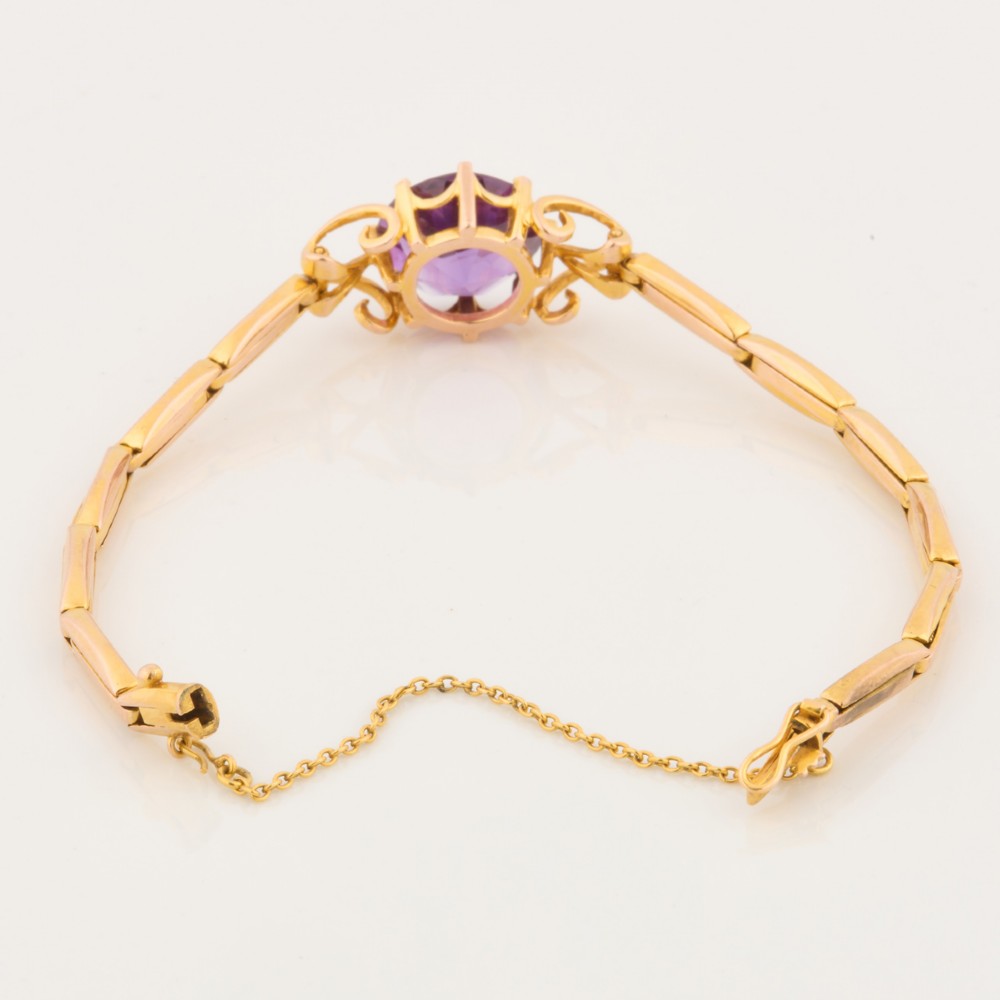 A 9ct yellow gold link bracelet featuring a central round faceted purple amethyst held in a claw setting. View IV