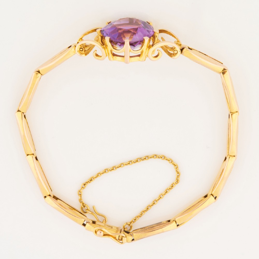 A 9ct yellow gold link bracelet featuring a central round faceted purple amethyst held in a claw setting. View V