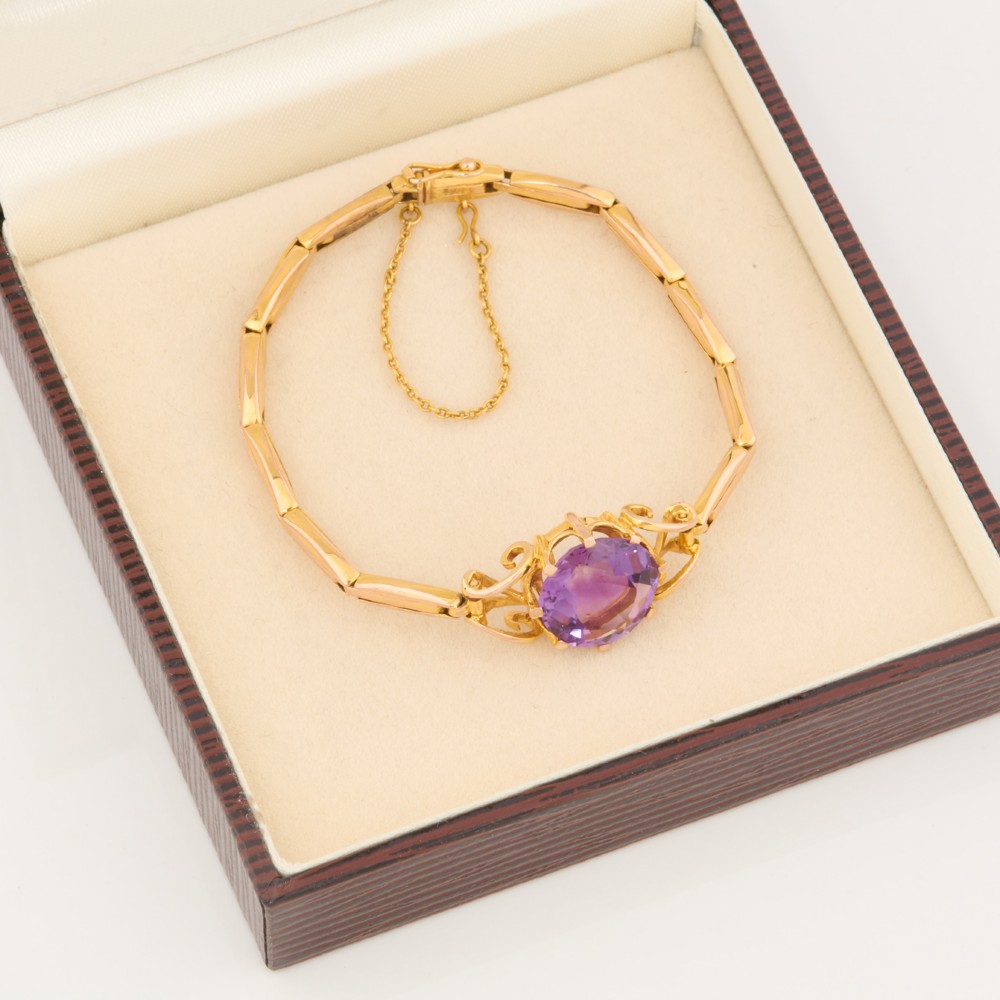A 9ct yellow gold link bracelet featuring a central round faceted purple amethyst held in a claw setting. View VII