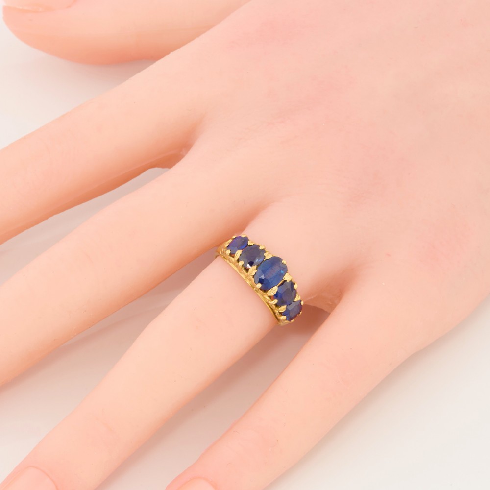 An eighteen-carat yellow gold ring featuring five graduated oval blue sapphires set in a carved claw setting. View II