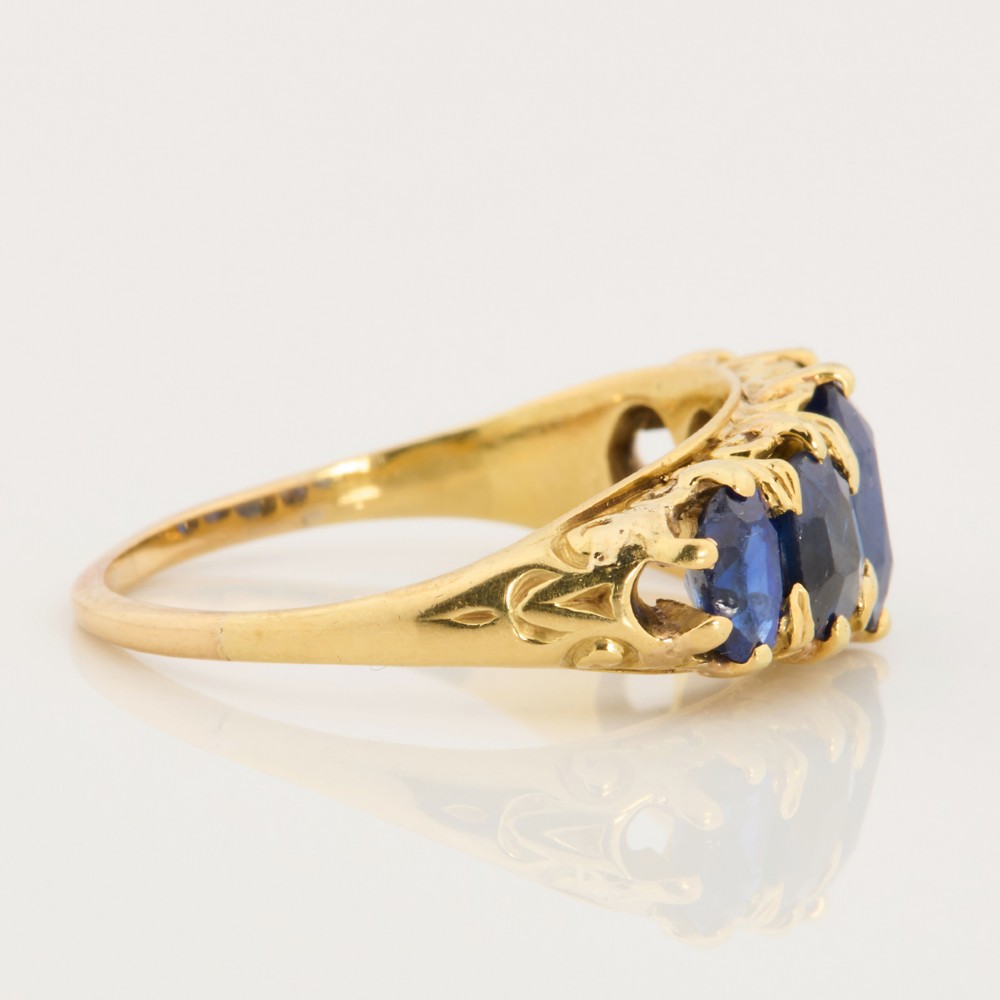 An eighteen-carat yellow gold ring featuring five graduated oval blue sapphires set in a carved claw setting. View IV