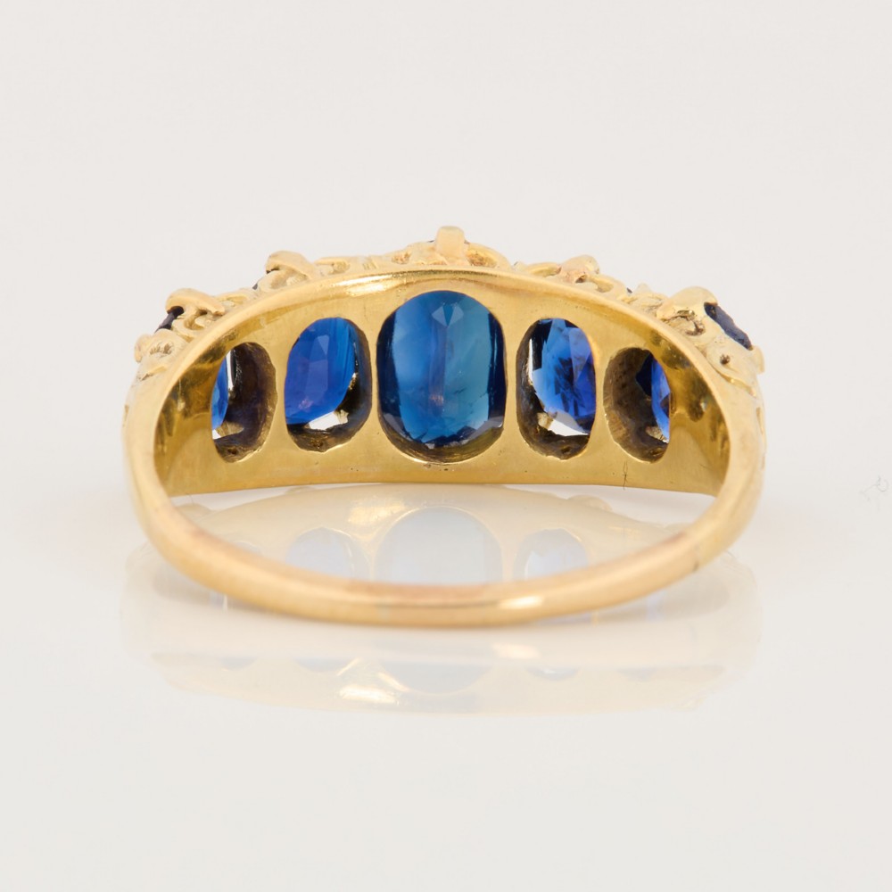 An eighteen-carat yellow gold ring featuring five graduated oval blue sapphires set in a carved claw setting. View V