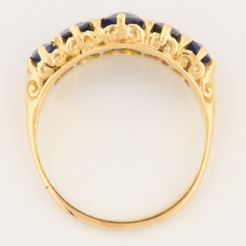 An eighteen-carat yellow gold ring featuring five graduated oval blue sapphires set in a carved claw setting. View VI