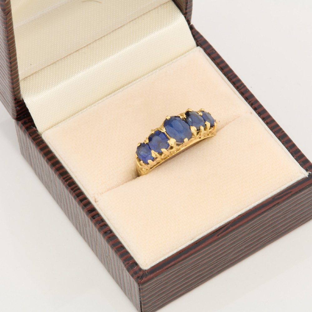 An eighteen-carat yellow gold ring featuring five graduated oval blue sapphires set in a carved claw setting. View VII