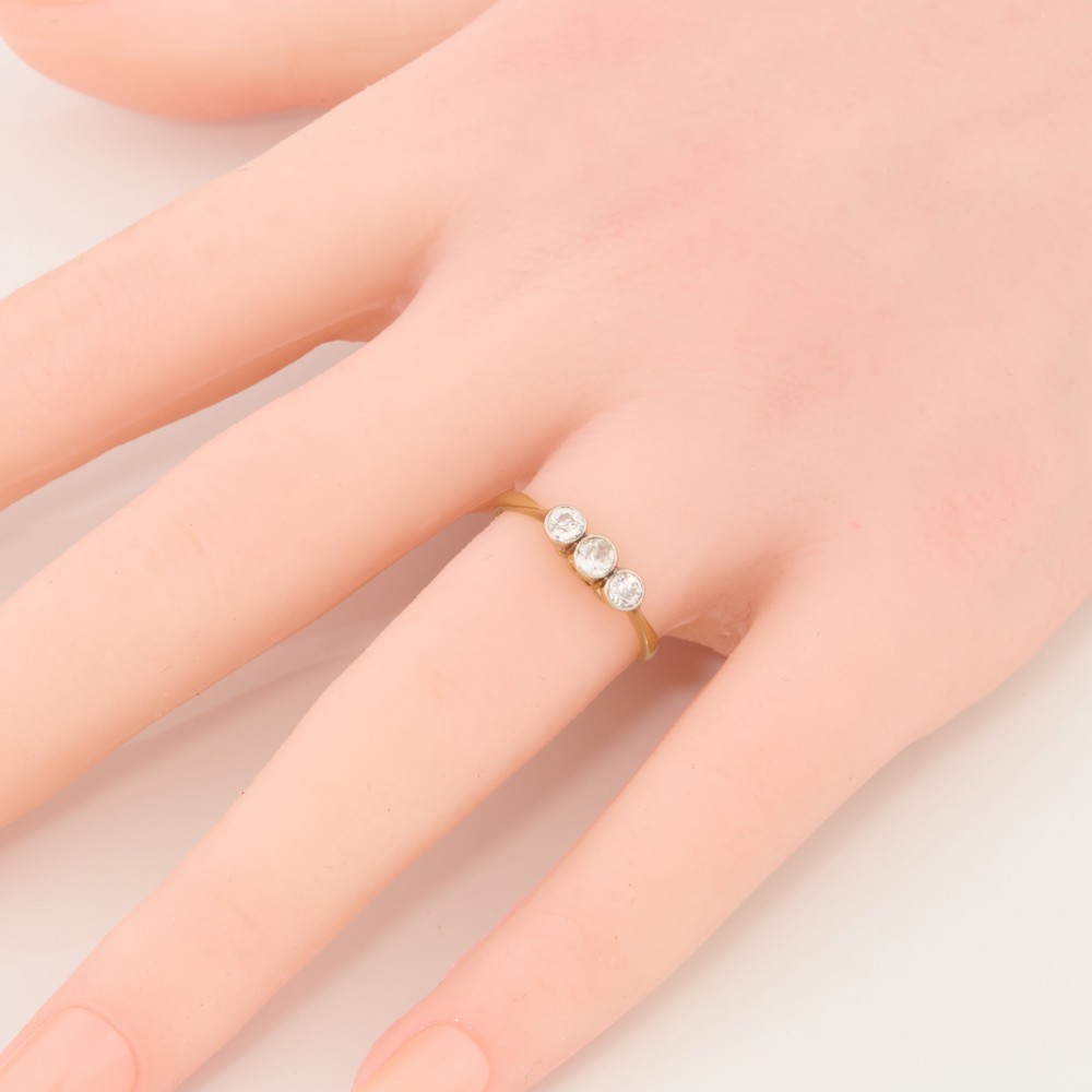 An 18ct yellow gold trilogy ring featuring three round diamonds set in platinum rub-over settings. View II