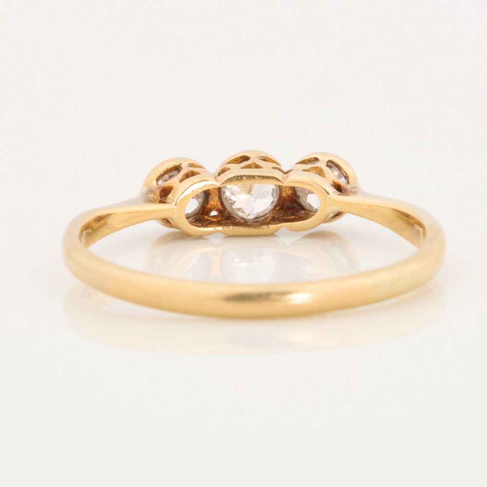 An 18ct yellow gold trilogy ring featuring three round diamonds set in platinum rub-over settings. View V