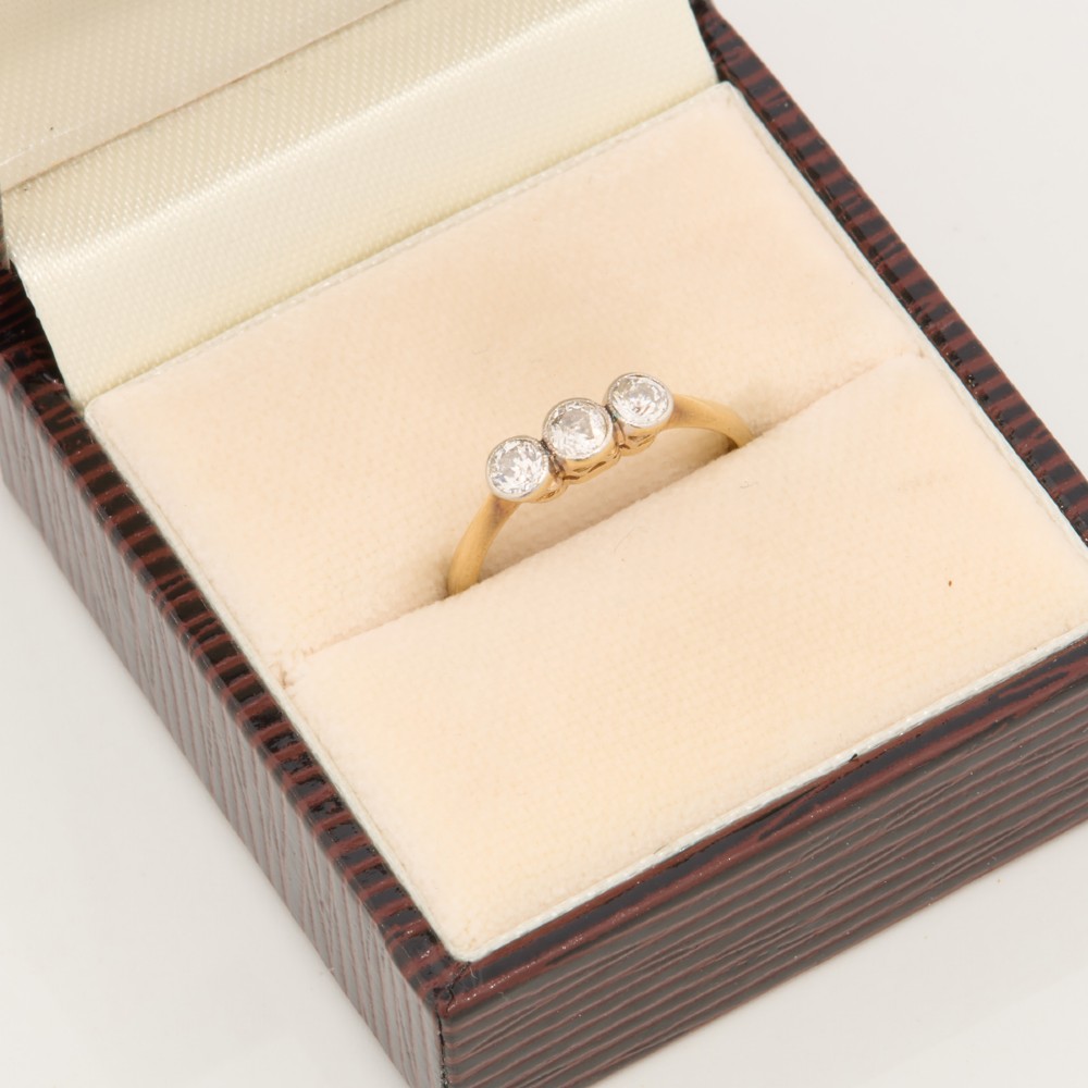 An 18ct yellow gold trilogy ring featuring three round diamonds set in platinum rub-over settings. View VIII