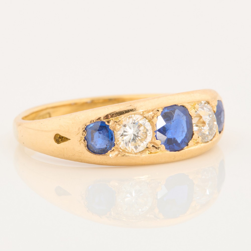 An 18ct yellow gold five-stone ring featuring three round blue sapphires alternating with two round diamonds in a carved boat-style gallery. View III