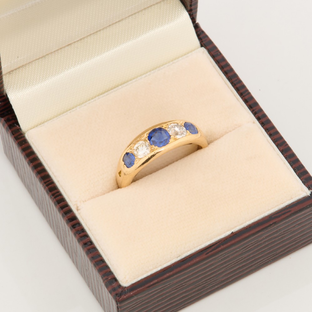 An 18ct yellow gold five-stone ring featuring three round blue sapphires alternating with two round diamonds in a carved boat-style gallery. View VIII