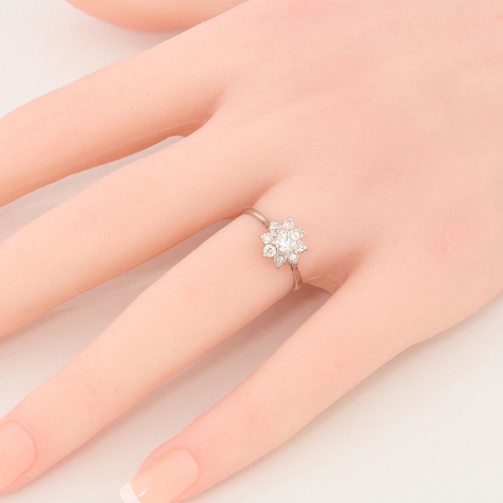 An 18ct white gold ring featuring a central round diamond encircled by eight smaller diamonds in a daisy cluster design. View II