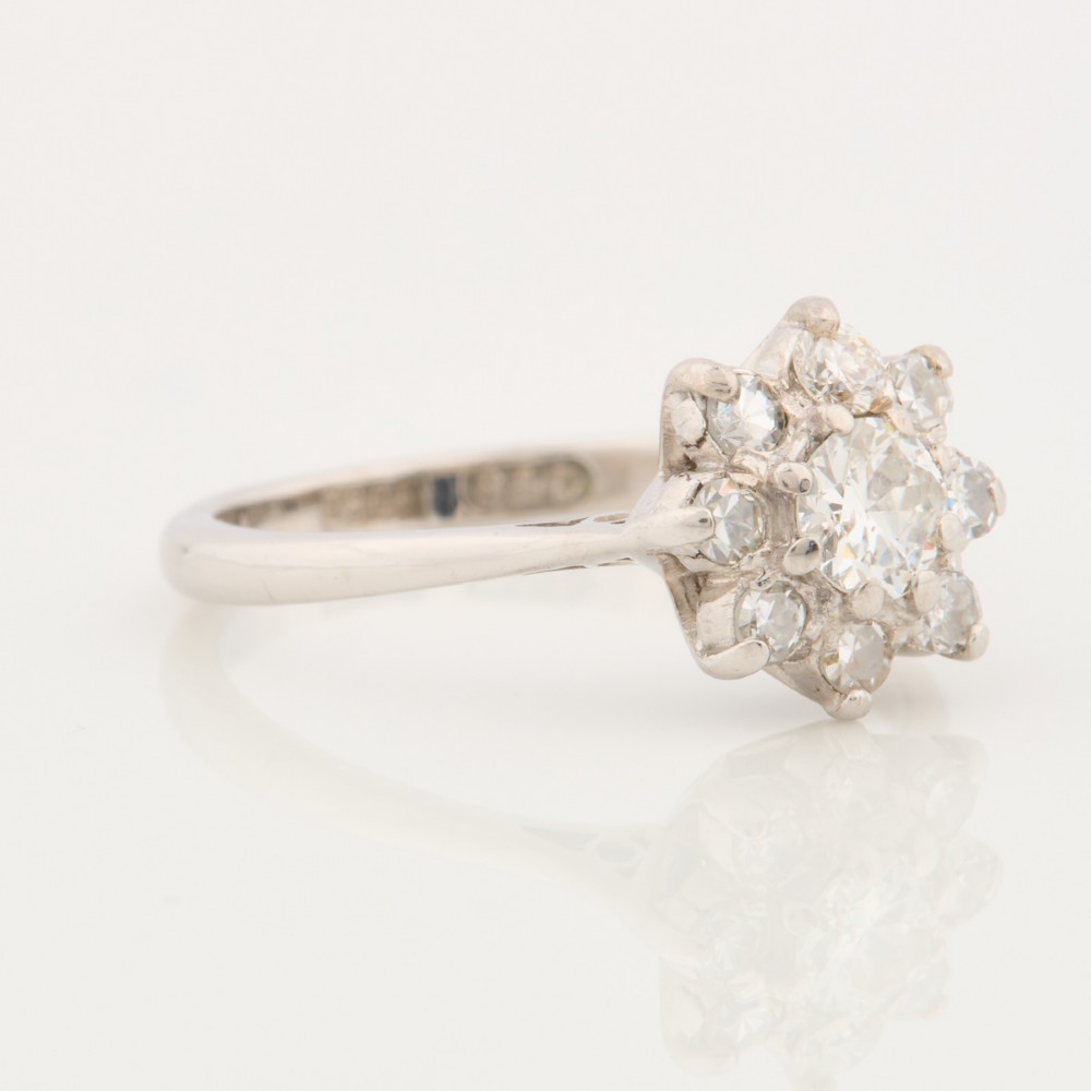 An 18ct white gold ring featuring a central round diamond encircled by eight smaller diamonds in a daisy cluster design. View III