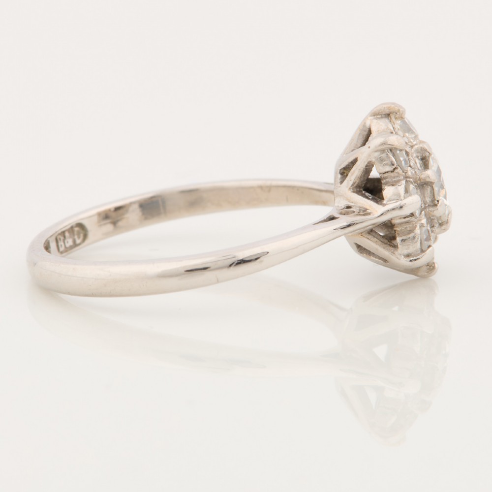An 18ct white gold ring featuring a central round diamond encircled by eight smaller diamonds in a daisy cluster design. View IV