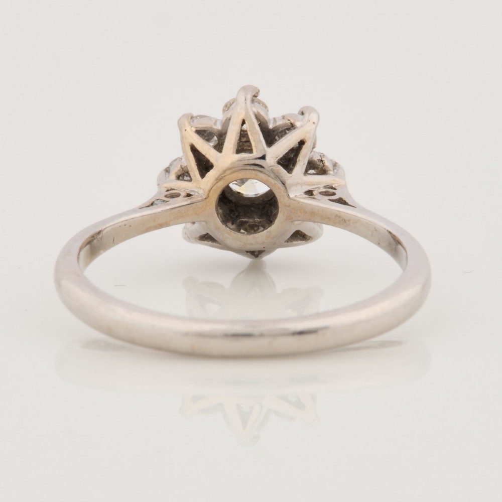An 18ct white gold ring featuring a central round diamond encircled by eight smaller diamonds in a daisy cluster design. View V