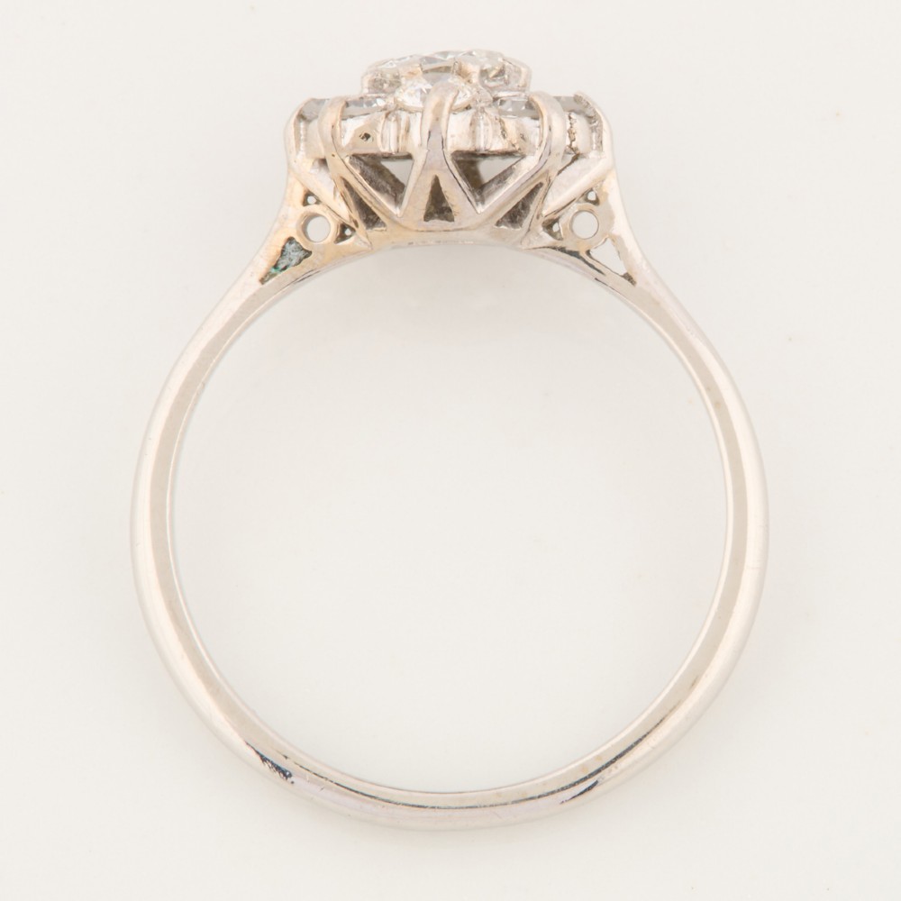 An 18ct white gold ring featuring a central round diamond encircled by eight smaller diamonds in a daisy cluster design. View VI