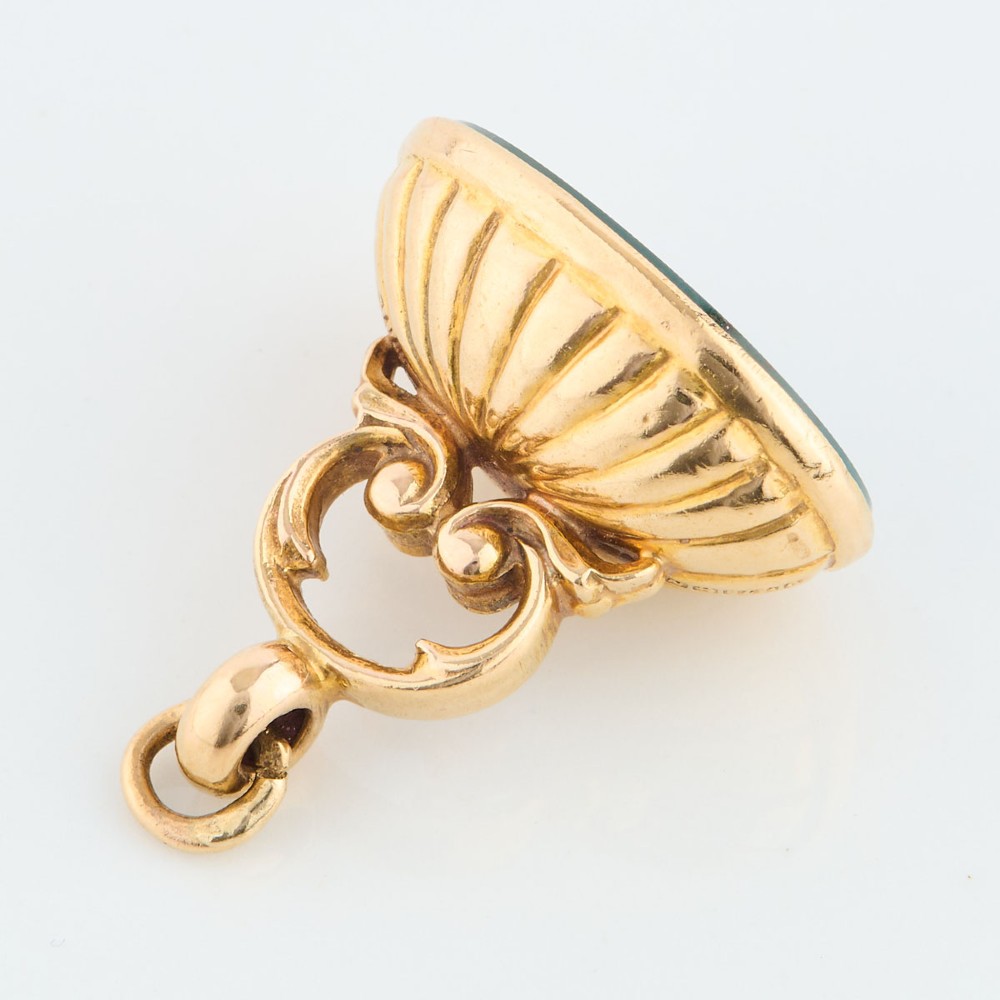 An antique 9ct gold fob mount holding a polished oval green bloodstone with red flecks, featuring fluted rim detail and an arched suspension bail. View IV