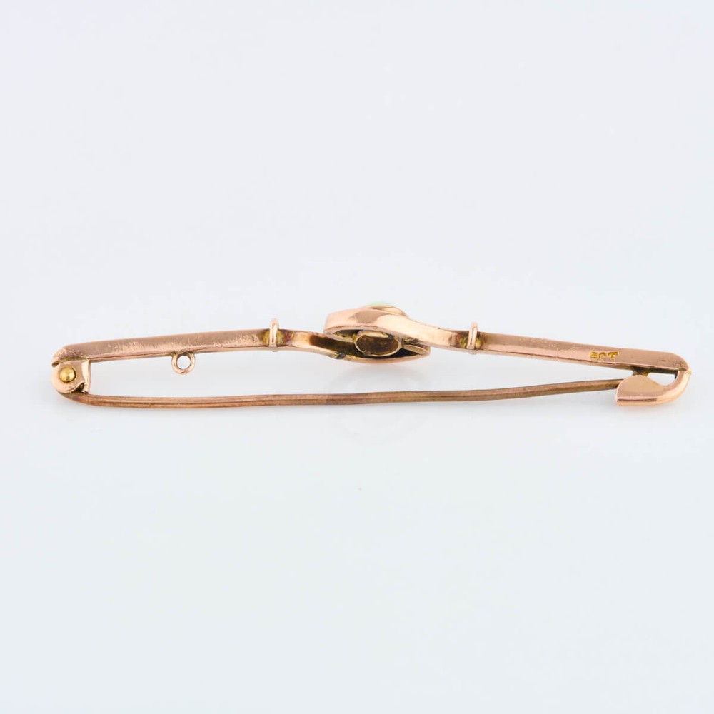 A 9ct yellow gold bar brooch featuring a central round cabochon opal in a bezel setting with a swirl wire accent. View III